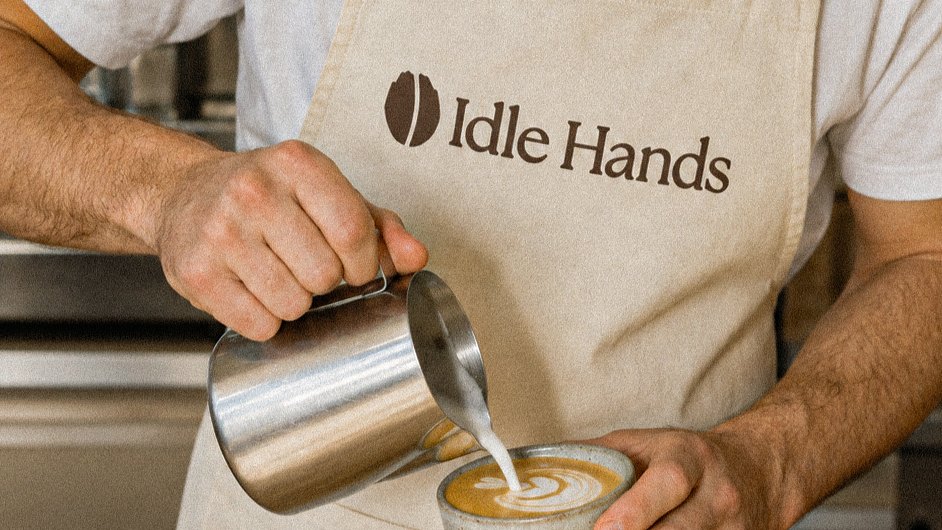 A barista in the Idle Hands apron pouring a flat white