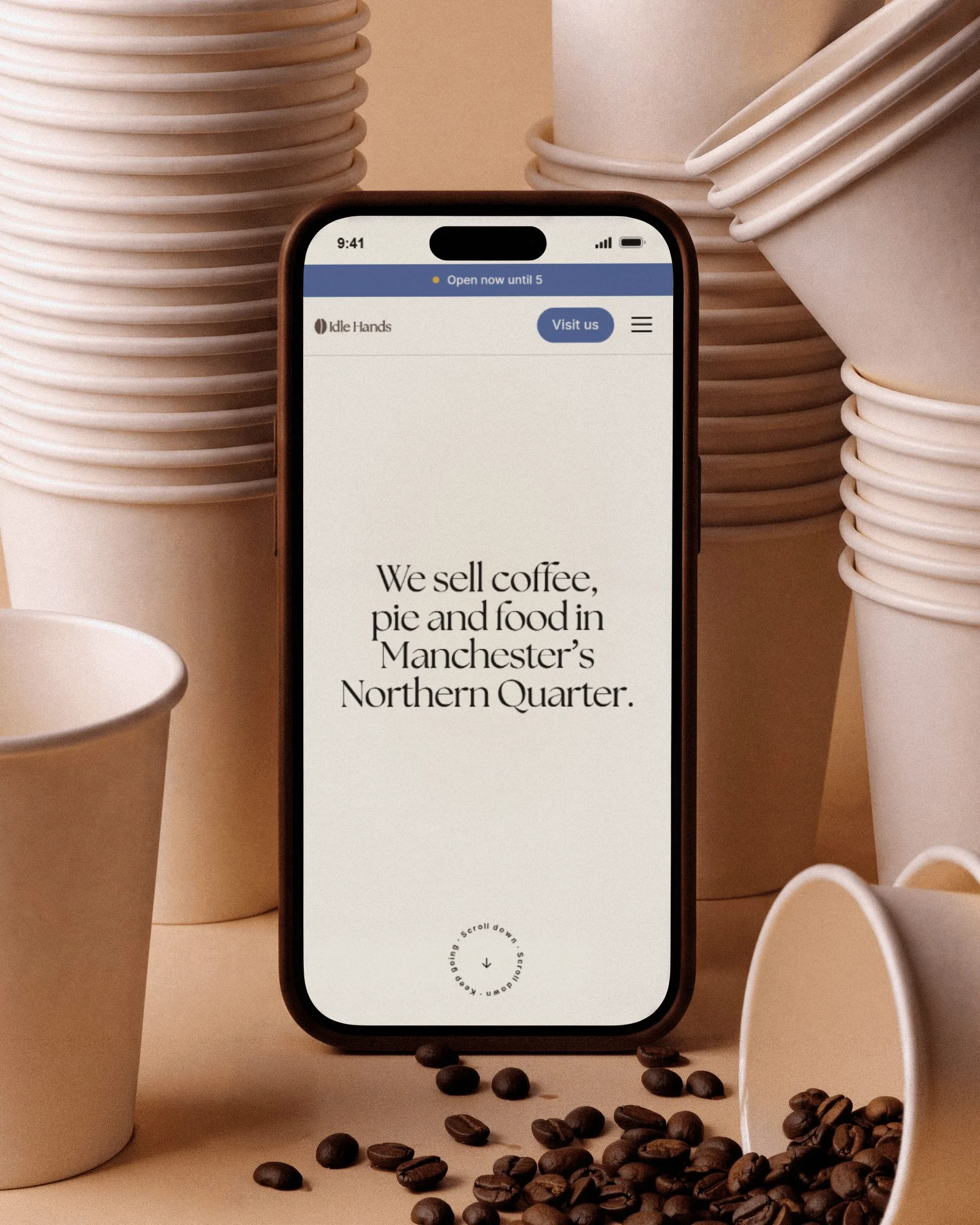 The Idle Hands site on a phone standing among paper cups and coffee beans