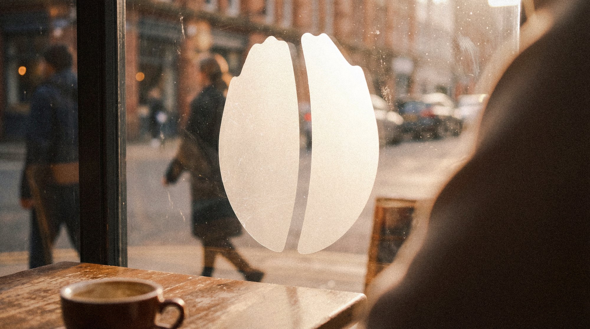 The bean mark frosted onto the café window, the street behind it