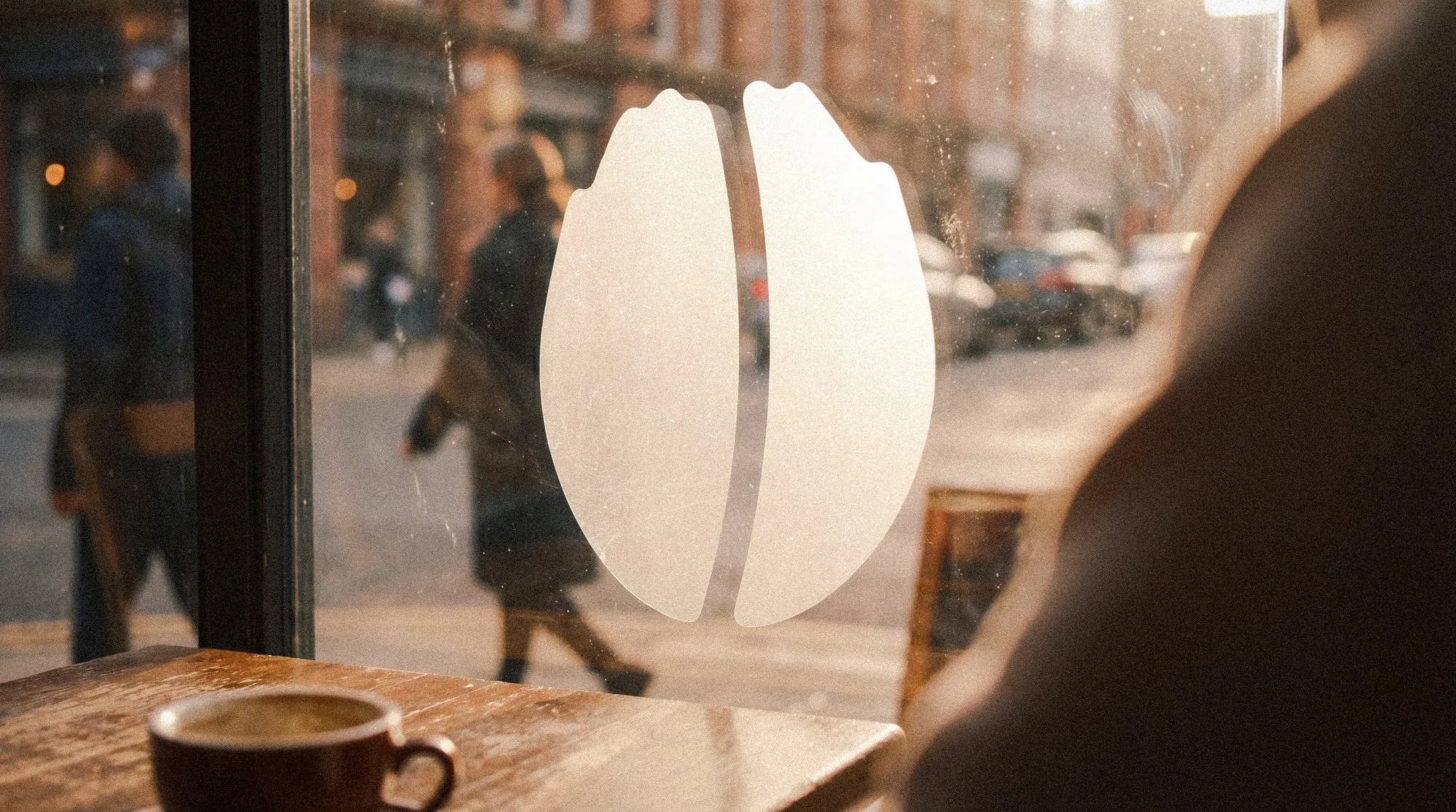 The bean mark frosted onto the café window, the street behind it